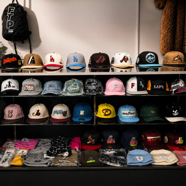 Shelf displaying various baseball caps with different logos and designs.