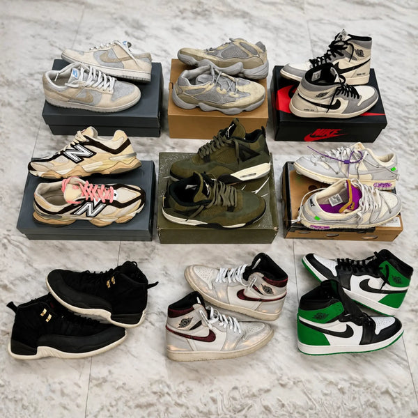 Collection of various sneakers displayed on a marble surface with boxes.